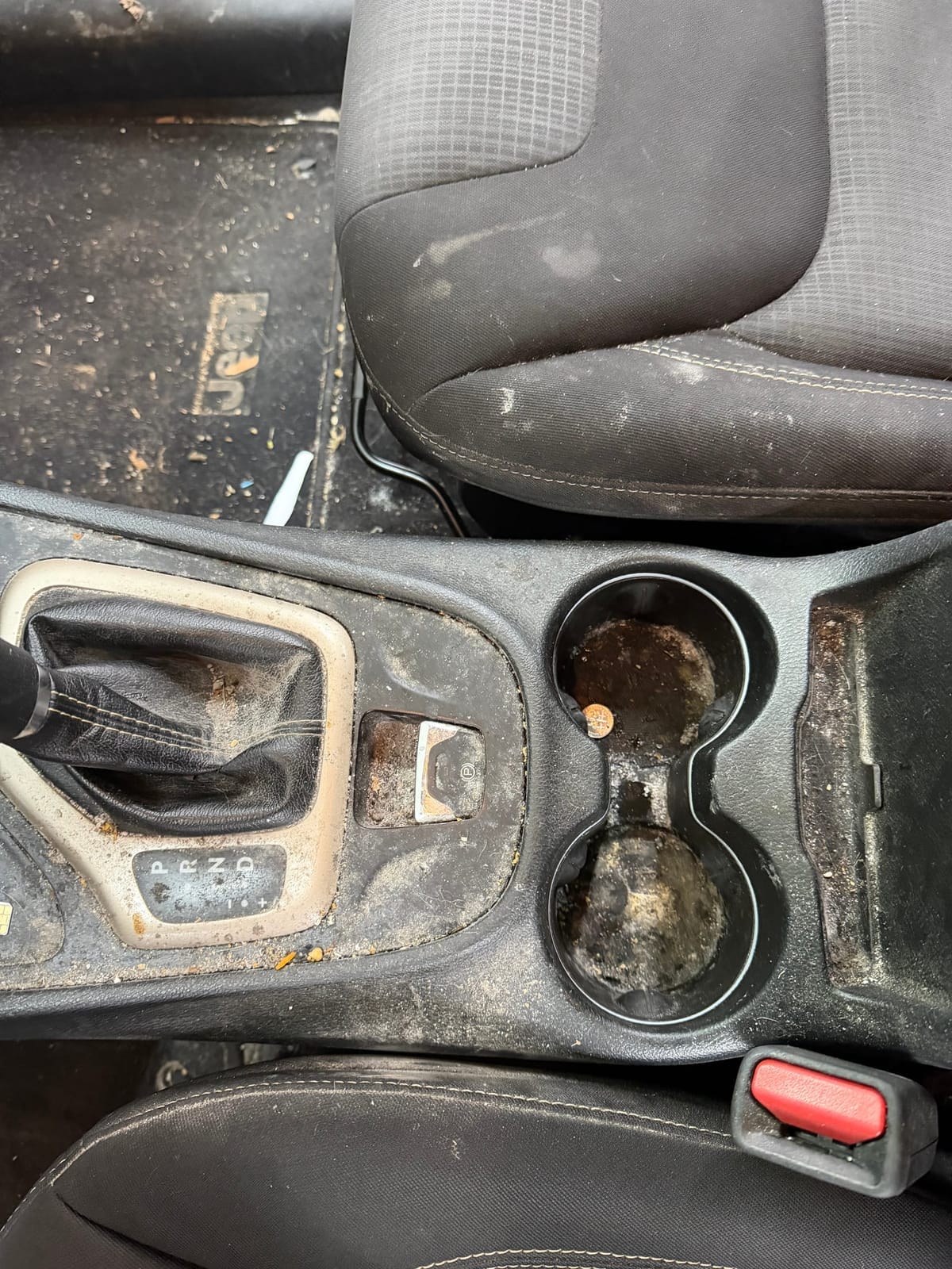 Vehicle center console with debris and grime before Fitchin Automotive interior detail — Coshocton, Ohio